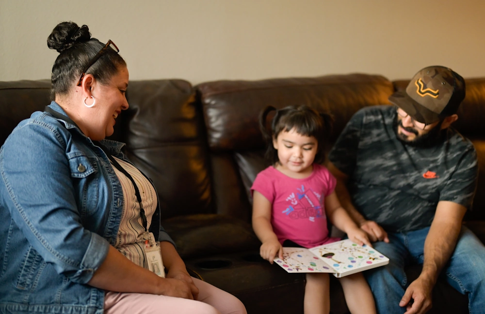 Parents sitting with child reading a book