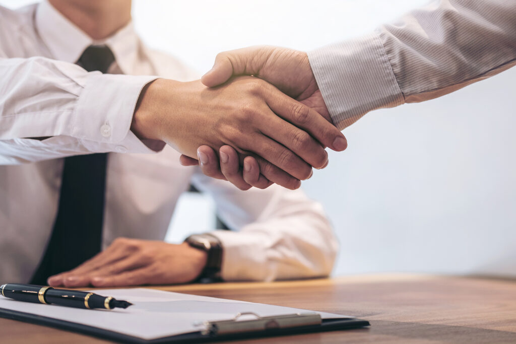 Men shaking hands over a desk and signed paperwork