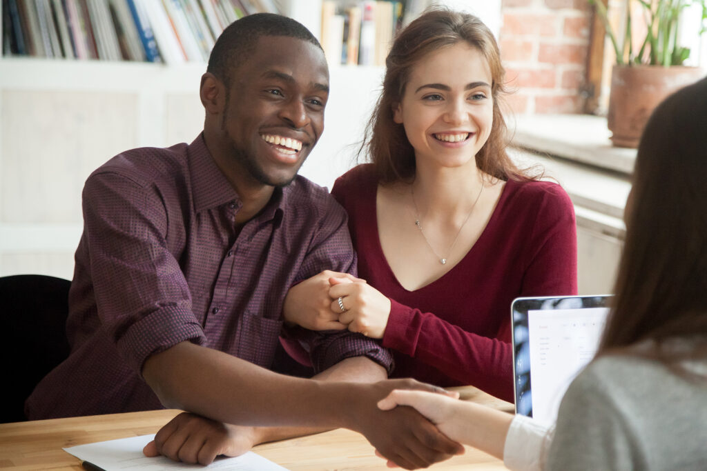 Smiling couple shaking hands with financial advisor